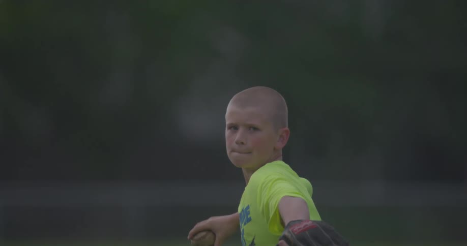 A boy with a shaved head throws a ball