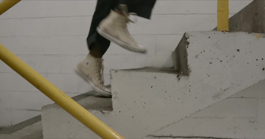A young black male runs swiftly up a set of concrete stairs