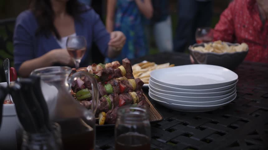 A woman in a blue shirt reaches for a plate