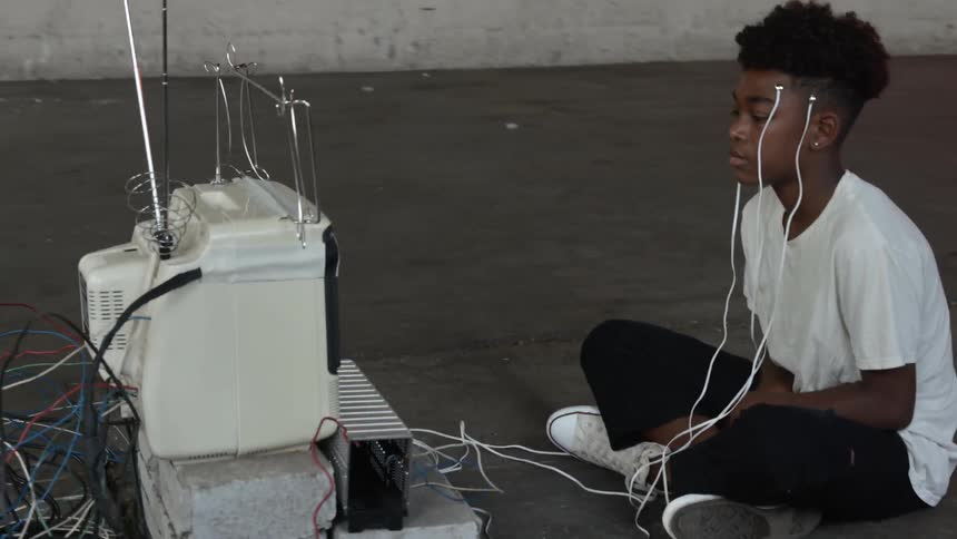 A black boy sitting in front of a display