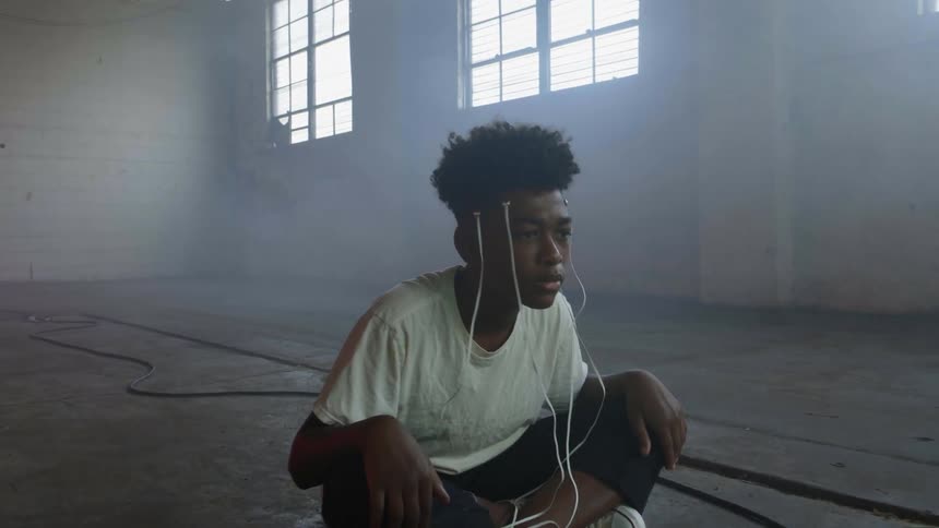 A teenager stares at a television while electrodes are connected to his head