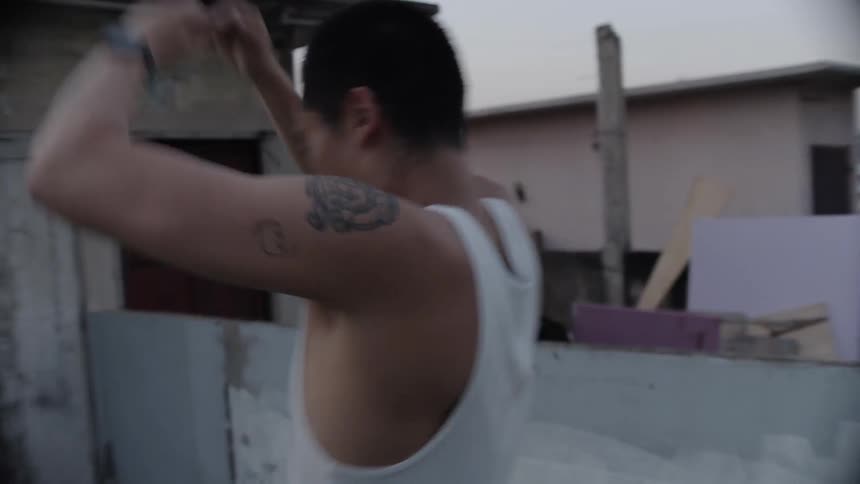A man on a city rooftop shadow boxes and kicks