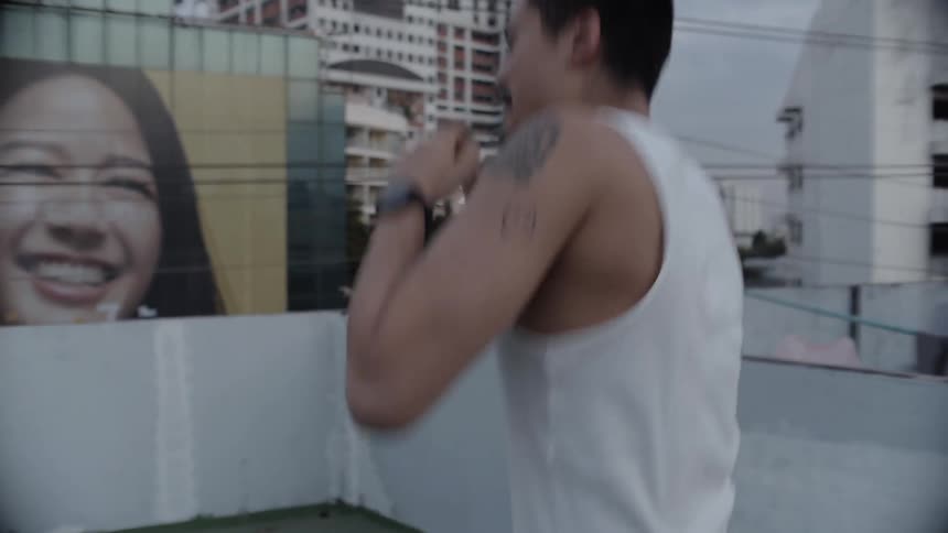 Man shadow boxing outdoors on a rooftop deck