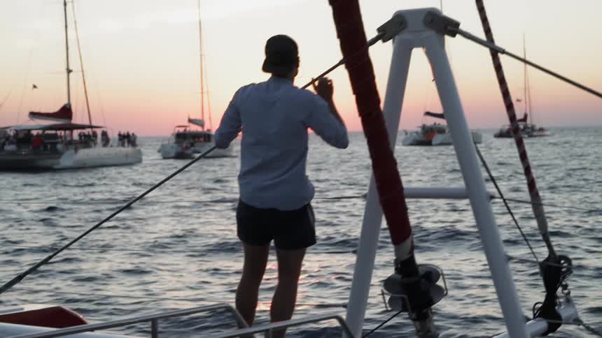 A man hangs on a rope on the side of a boat