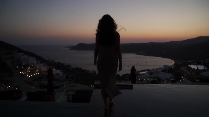 A woman walks across a rooftop that looks over a neighborhood