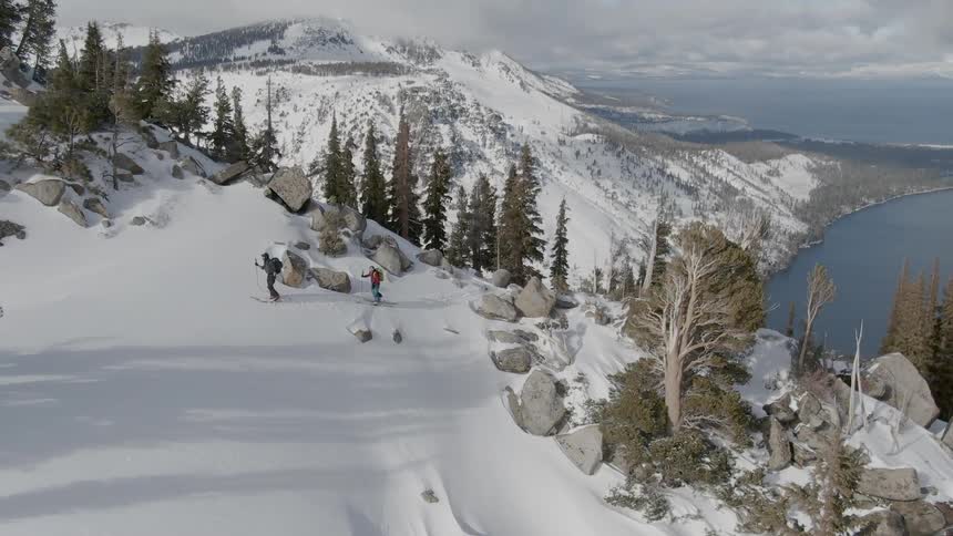 Two people cross country ski on the side of a mountain