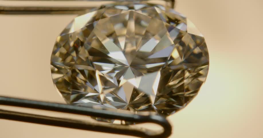 Pincers rotate sparkling faceted diamond