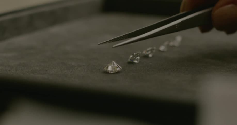 A person uses tweezers to flip of a diamond stone