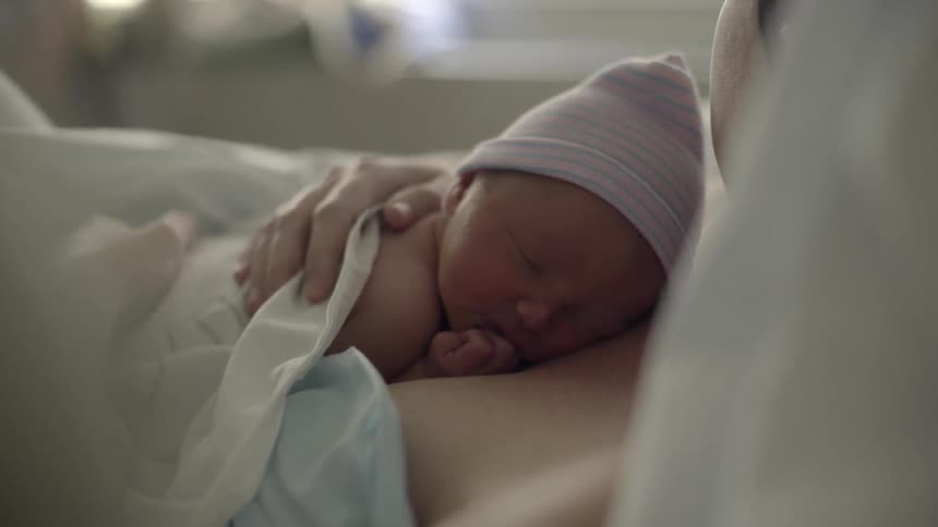 A woman rubs the baby on her chest