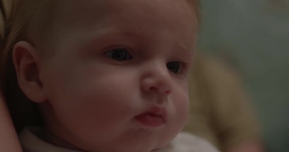 A baby sits on a woman's lap