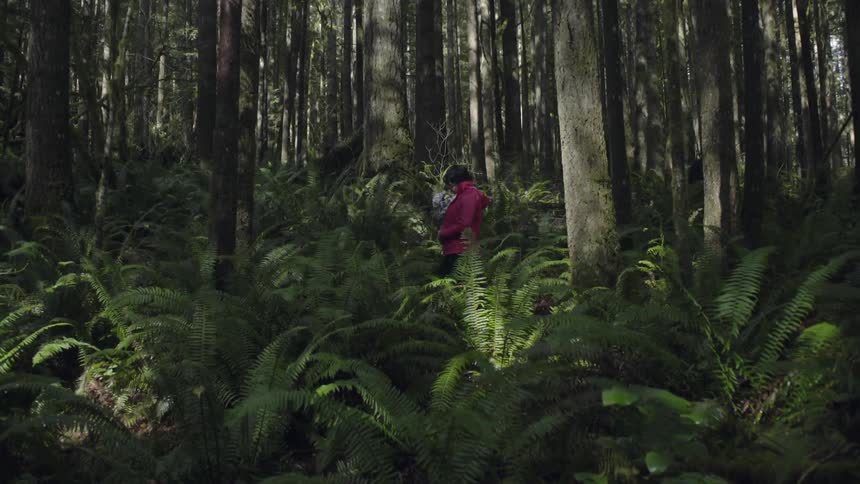 A woman sways slightly as she holds her baby in the forest