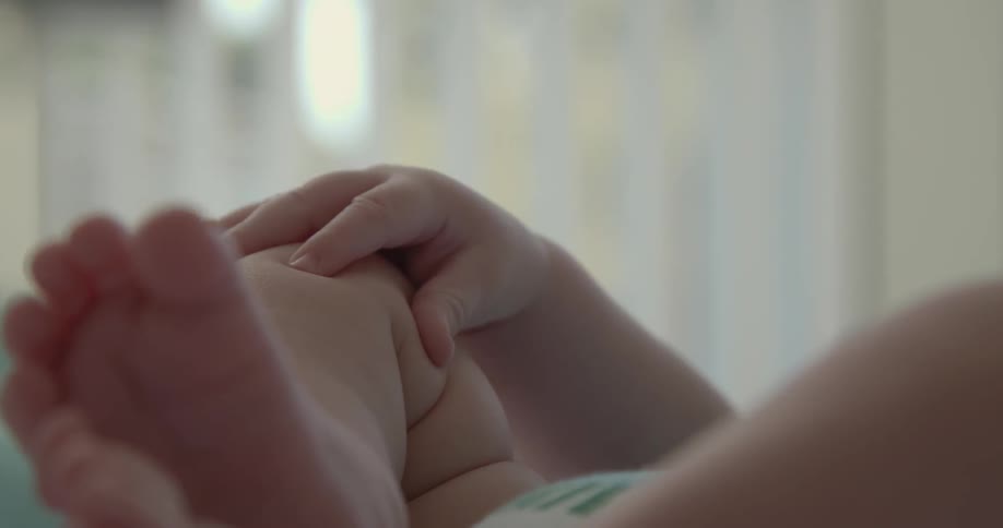 A baby's hand squeezes its own chubby knee