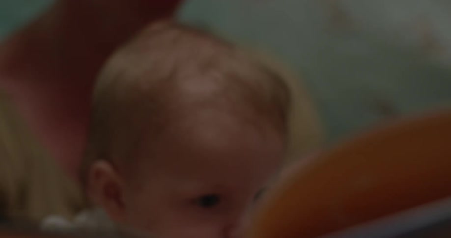 A woman reads a book to a baby in her lap