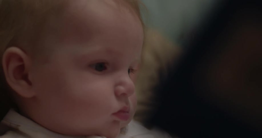 A baby sits peacefully on a woman's lap