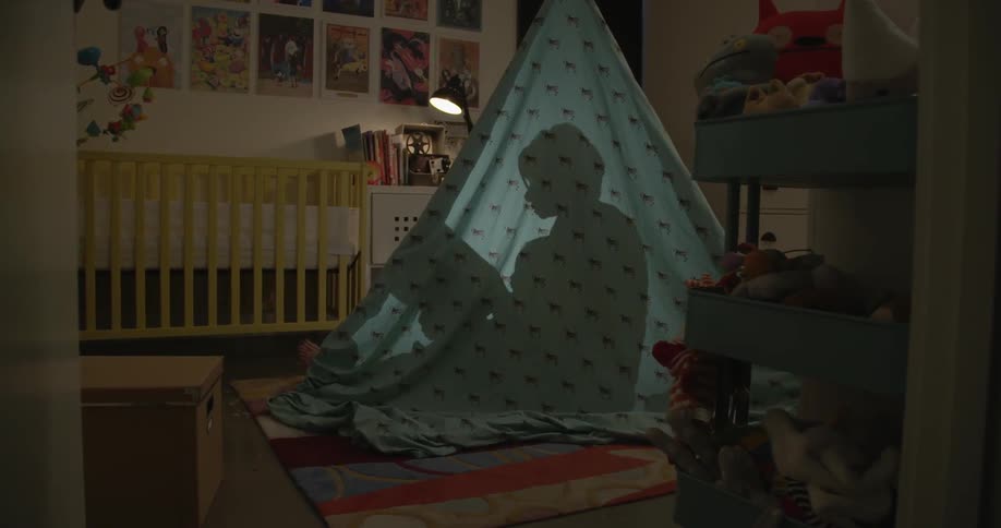 The silhouette of a person holding a baby and a book
