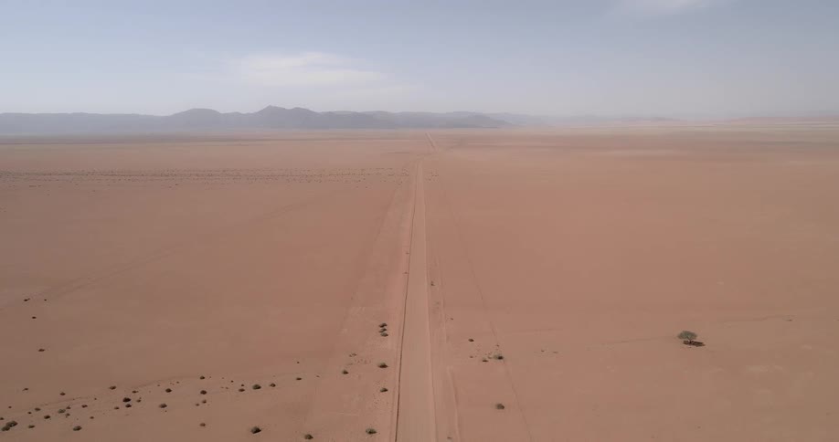 A large flat desert with a sandy road