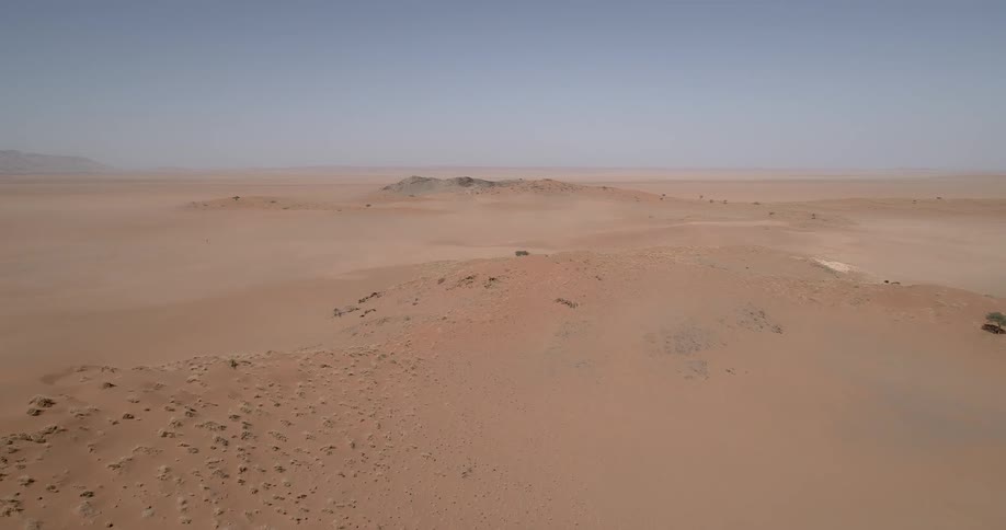 Sand dunes rock and brush under a blue sky in the desert