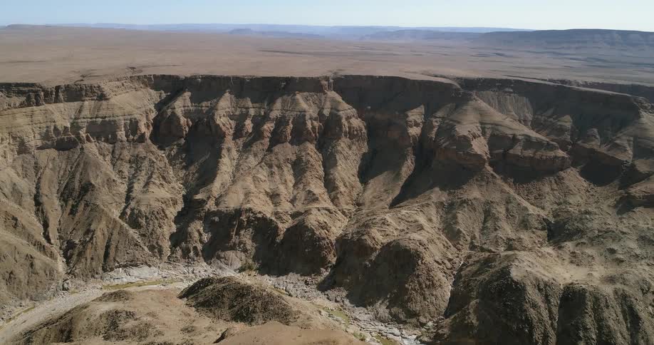 A canyon with a dry riverbed cuts through a flat stretch of land