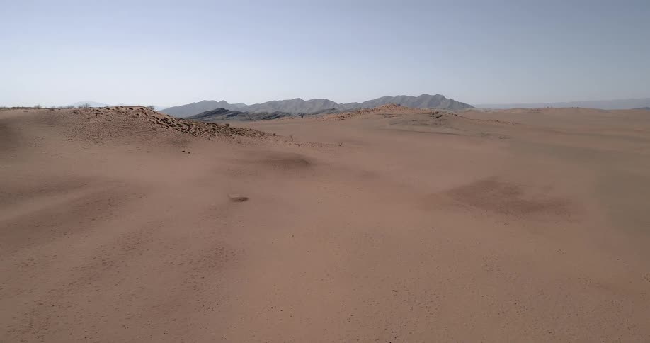Sand covers a hilly desert landscape on a clear day