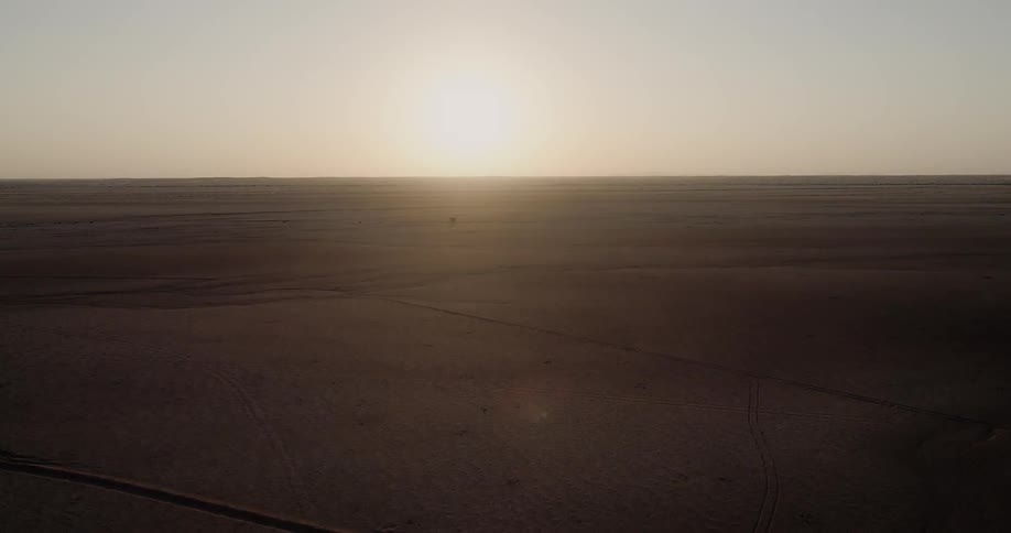Sun rises on the horizon of plain dotted with scrub and crossed by roads and trails