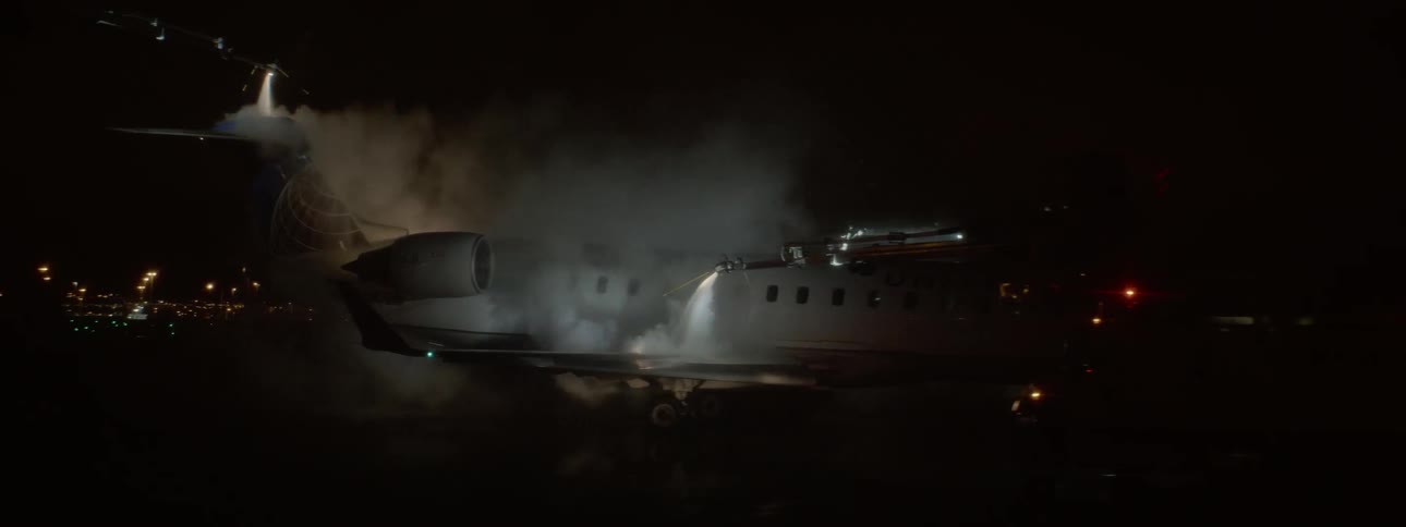 An airplane is sprayed with a liquid on a runway at night