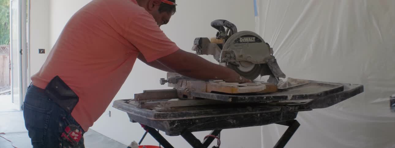 A man with a buzz saw cutting wood on a sliding table