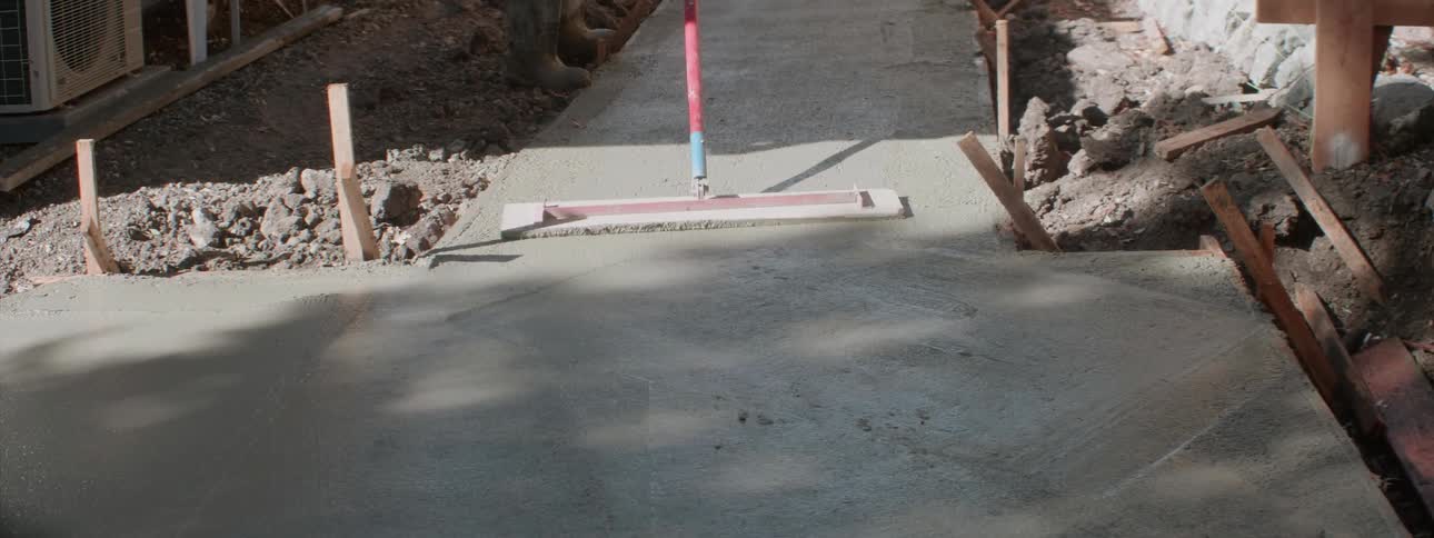 Workers are laying a concrete sidewalk