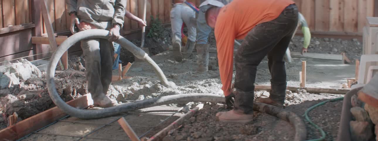 A group of construction workers are laying fresh cement