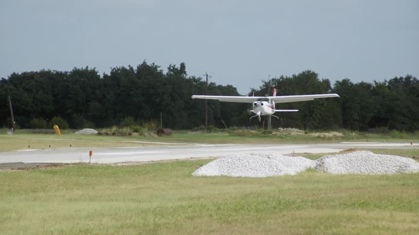 Cessna plane landing on a small runway in a rural area