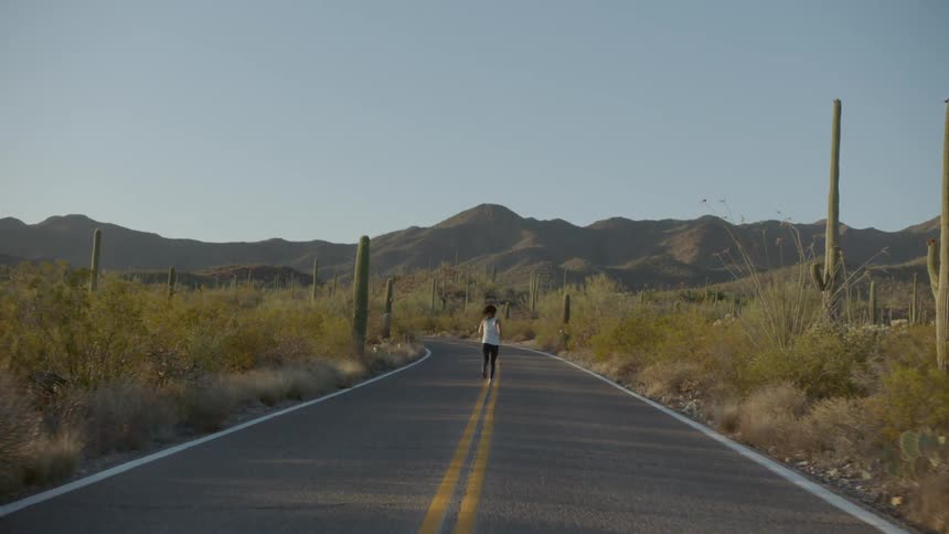 A woman is jogging down a road in a rural area