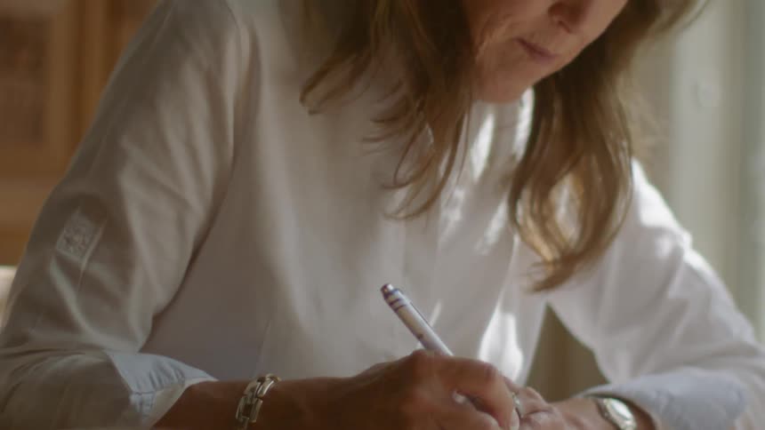 Woman sitting at a table writing in a notebook