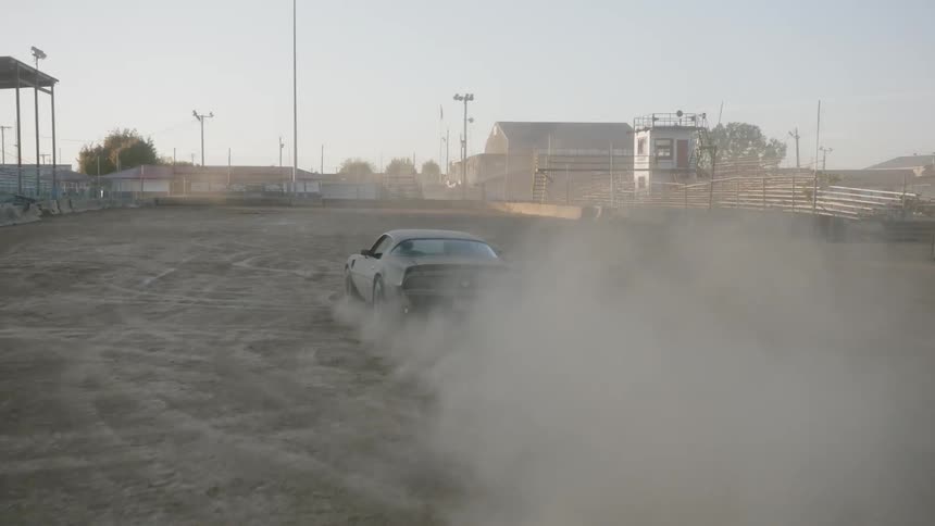 A car races through a dirt arena
