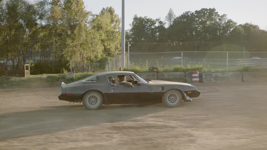 Dust flies by as a car races through a dirt field