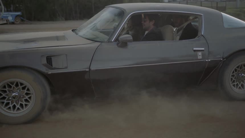 A young man drives a car with two passengers in it