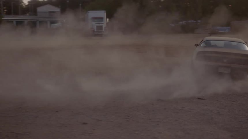 A muscle car doing donuts in the dirt