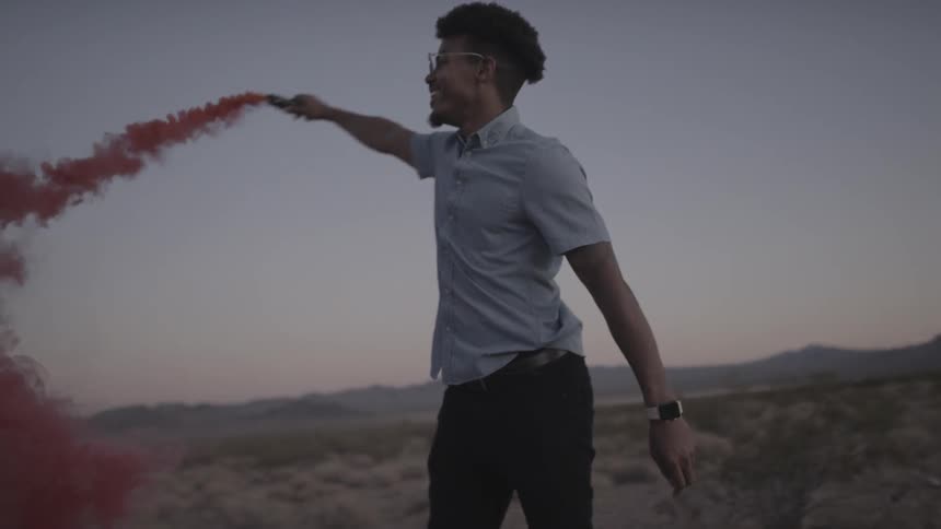 A man turns in circles while releasing colored powder from a tube
