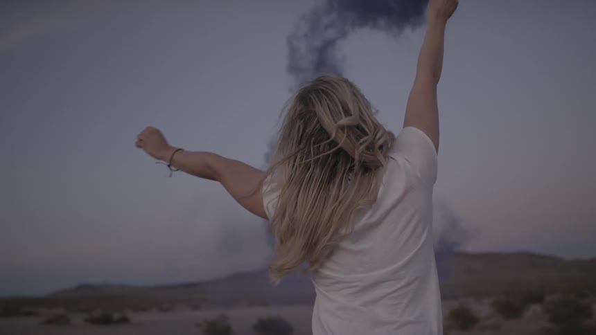 A woman circles with blue smoke