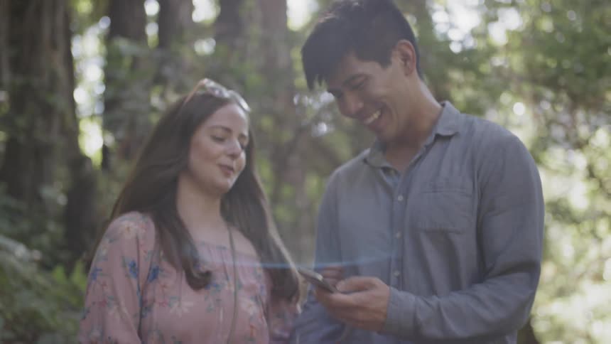 Two people looking at a phone in the forest