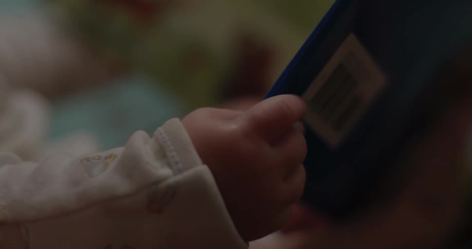 A baby's hand grasps at a book being read to him/her