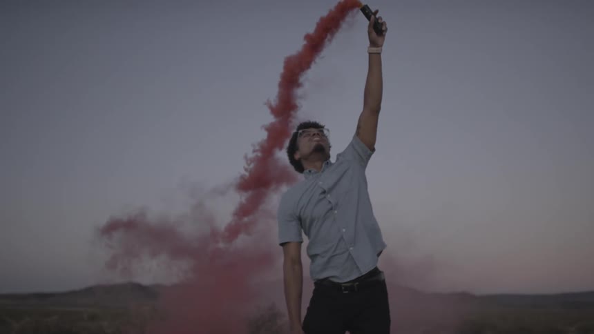 A man happily pours red smoke