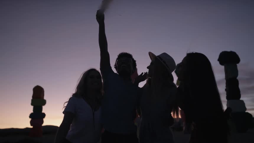A person holds up a smoke flare in a group