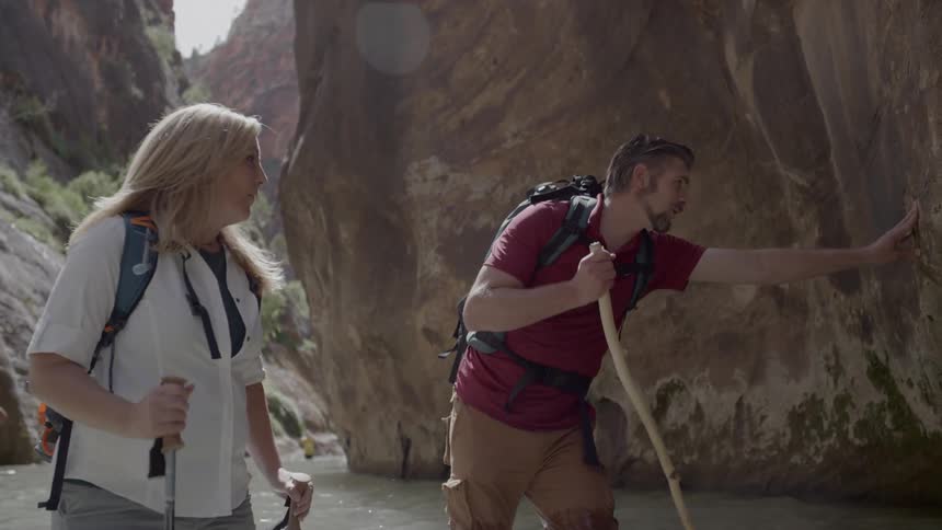 Man and woman wade through water in gorge