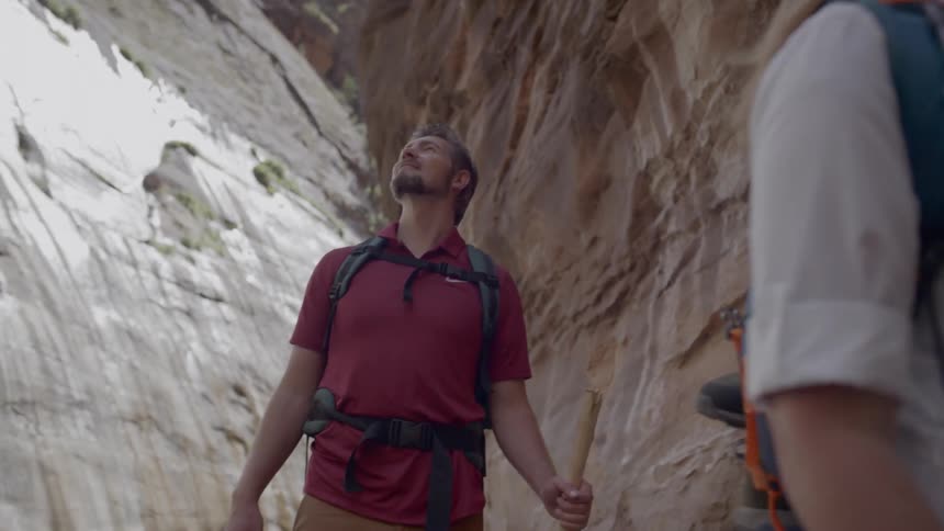 A man and woman look up at the mountain while hiking
