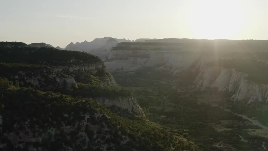 A wide canyon is situated between a range of mountains and plateaus