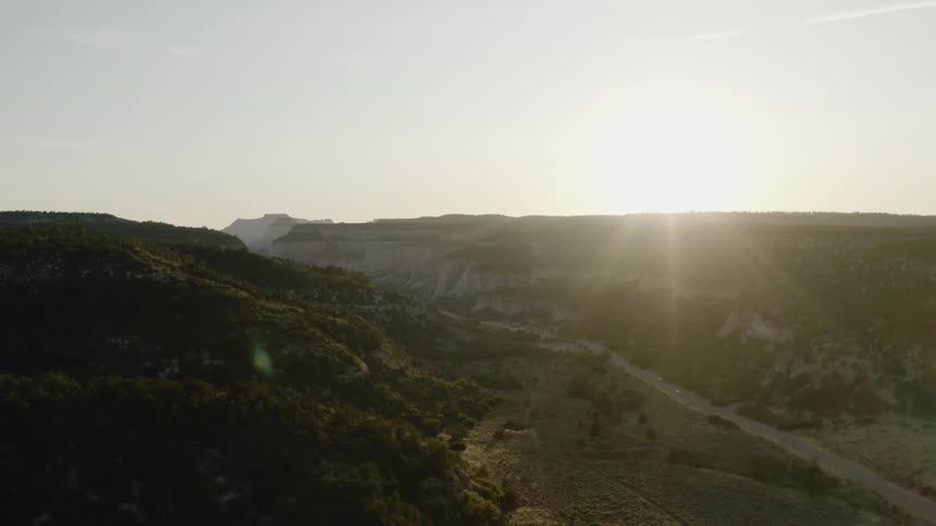 The sun rises over rolling hills and plateaus