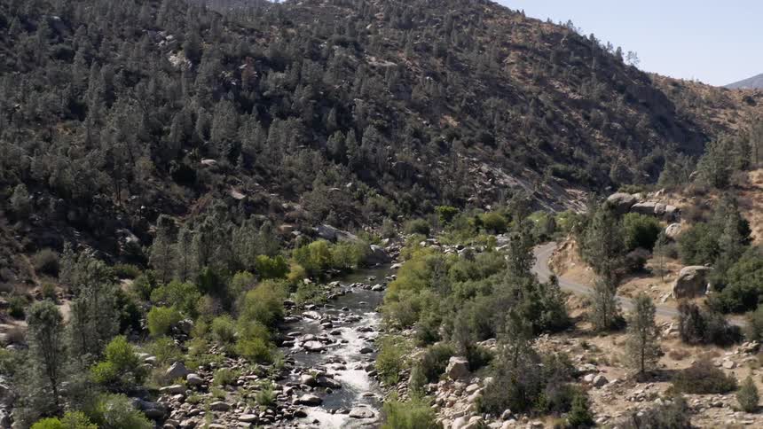 Aerial of a riverbed alongside a road in the canyon