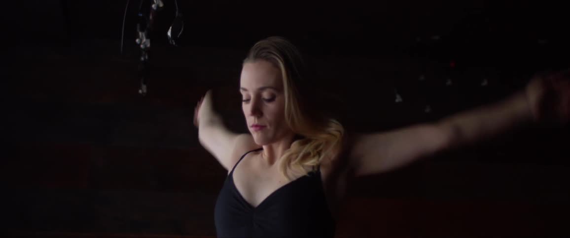 A dancer stretches her arms and shoulders
