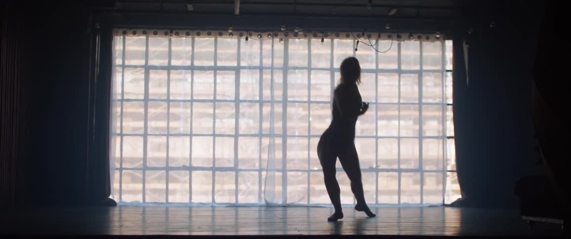 A female dances in silhouette in a dark room