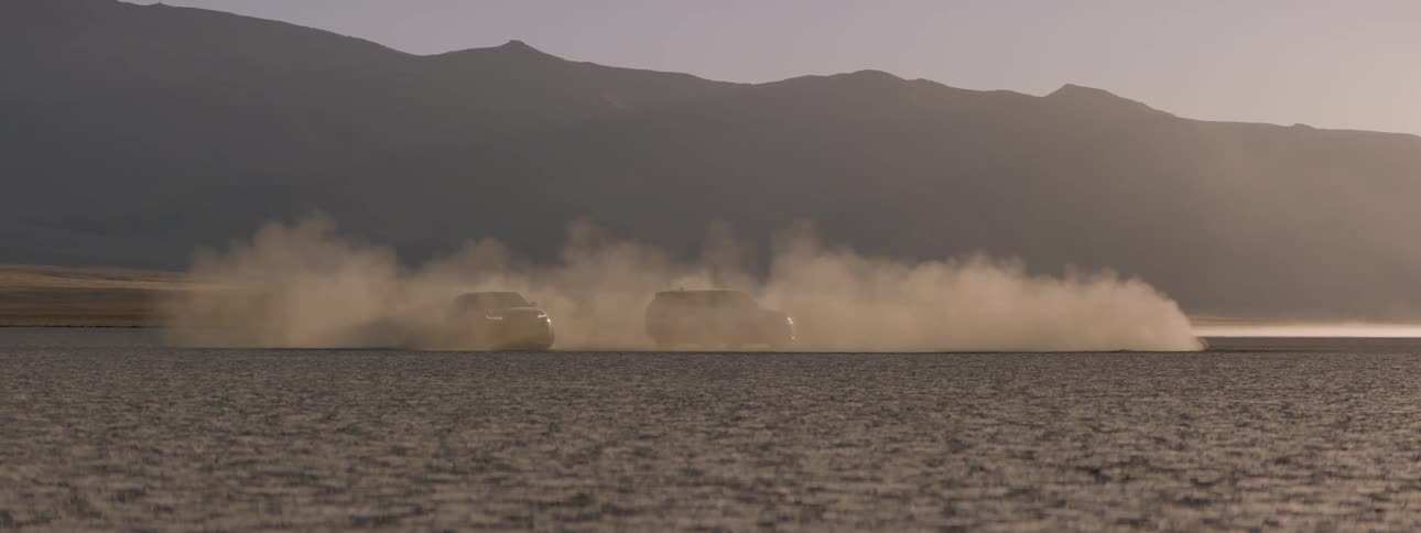 A car drives in circles around a stationary vehicle in the desert