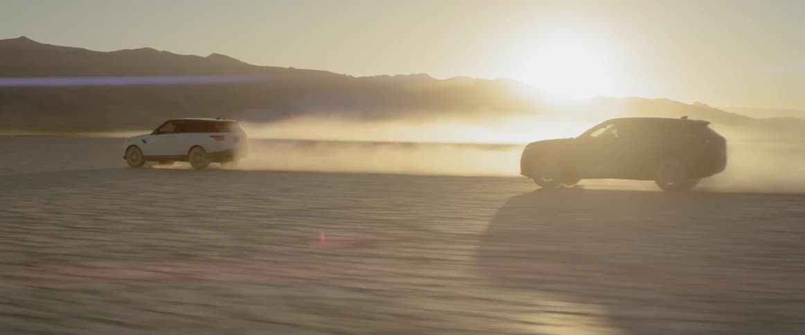 Two sports utility vehicles speed across a wide open dirt covered plain